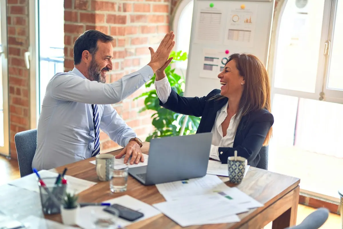 Directivo y consultora celebrando un buen resultado en una reunión de trabajo sobre certificación ISO